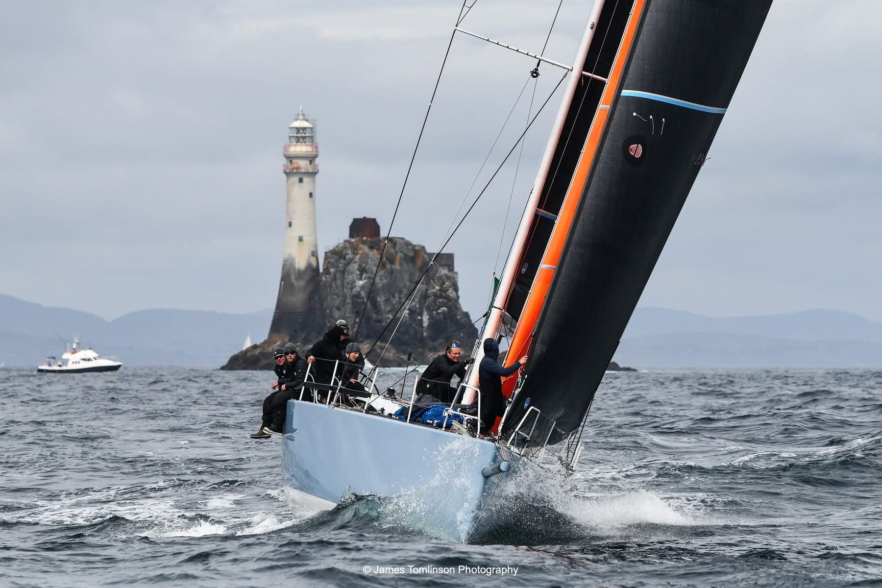 Moana am Fastnet Rock, Crew auf der Kante, schwarzes Vorsegel mit orangem Achterliek